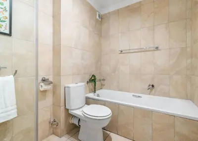 a bathroom with a toilet and a bath tub at The Tygervalley Escape in Cape Town