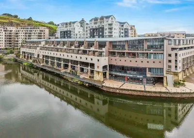 a building next to a body of water with buildings at The Tygervalley Escape in Cape Town