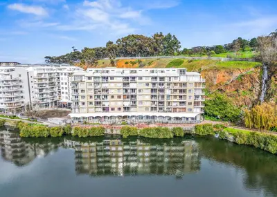 an apartment building next to a body of water at The Tygervalley Escape in Cape Town