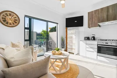 a white living room with a clock on the wall at Studio on North in Cape Town