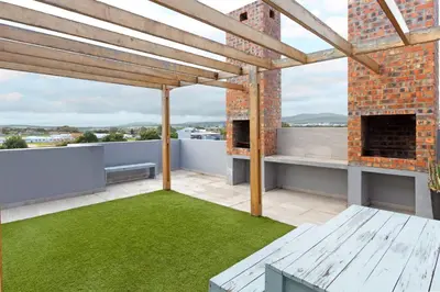 an outdoor patio with a brick fireplace and grass at Studio on North in Cape Town