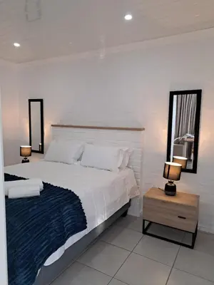 a bedroom with a large white bed and two lamps at Garden studio flat in Panorama
