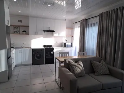 a kitchen and living room with a couch and a table at Garden studio flat in Panorama