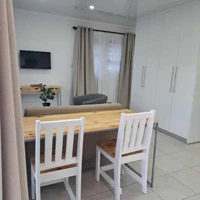 a kitchen with a table and two white chairs at Garden studio flat in Panorama