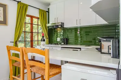 a kitchen with white cabinets and green tiles at Calais Wine Estate in Paarl