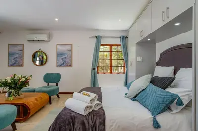 a bedroom with a bed and a chair and a window at Calais Wine Estate in Paarl