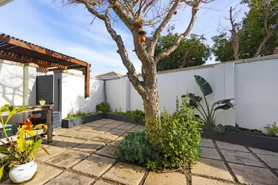 a patio with a tree and a white fence at Villa on 15th Waters Edge, Cape Town in Cape Town