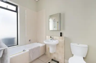 a bathroom with a sink and a toilet and a bath tub at Villa on 15th Waters Edge, Cape Town in Cape Town