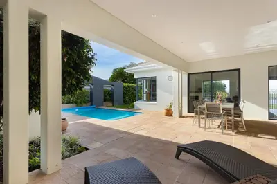 a patio with a pool and a table and chairs at Villa on 15th Waters Edge, Cape Town in Cape Town