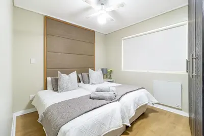 a bedroom with a large bed with a ceiling fan at 2 Bedroom Seaview, Holiday Apartment, Lagoon Beach in Cape Town