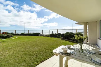 a patio with a table with a view of the ocean at 2 Bedroom Seaview, Holiday Apartment, Lagoon Beach in Cape Town