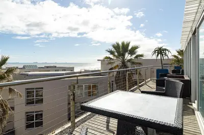 a balcony with a table and a view of the beach at 2 Bedroom Seaview, Holiday Apartment, Lagoon Beach in Cape Town