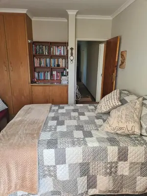 a bedroom with a bed and a book shelf with books at Fairway Corner in Villiersdorp