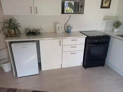 a kitchen with a black stove and white cabinets at 2 on Fifth Avenue in Botrivier