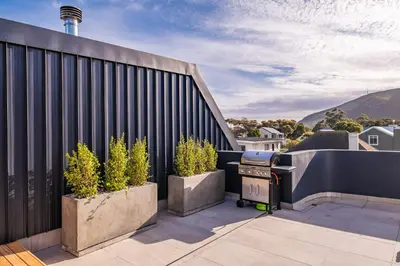a patio with two potted plants and a grill at Chic Coastal Hideaway in Hermanus