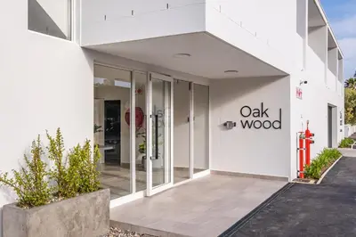 a white building with the oak wood sign on it at Chic Coastal Hideaway in Hermanus