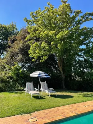 two chairs and an umbrella next to a pool at Honeymoon Stay at The James Family Farm in Grabouw