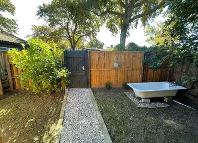 a bath tub sitting in a yard next to a fence at Honeymoon Stay at The James Family Farm in Grabouw