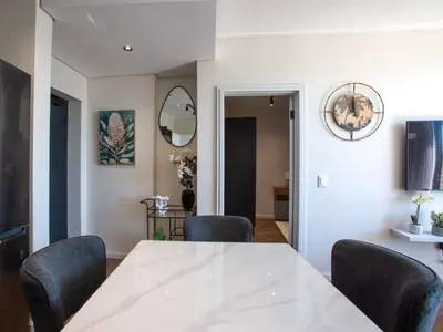 a dining room with a white table and chairs at On Park Century City in Cape Town