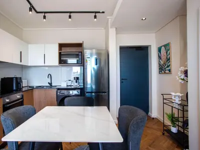 a kitchen with a table and chairs and a refrigerator at On Park Century City in Cape Town