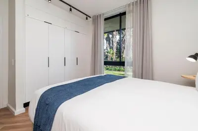 a white bedroom with a large bed and a window at Century City Natures Treat in Cape Town