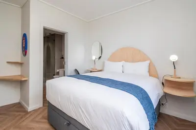 a bedroom with a large white bed and a mirror at Century City Natures Treat in Cape Town