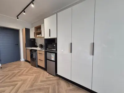a kitchen with white cabinets and a wooden floor at On Park - Century City Lux Studio Apartment in Cape Town