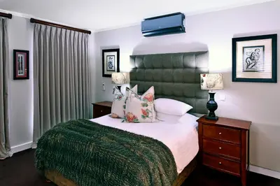 a bedroom with a large bed with a green headboard at Le Petit Bijou Aparthotel in Franschhoek
