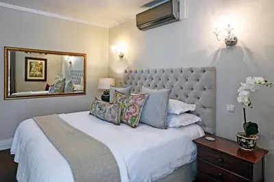 a bedroom with a large bed and a mirror at Le Petit Bijou Aparthotel in Franschhoek