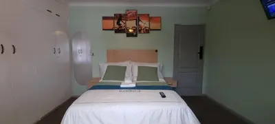a bedroom with a bed with white sheets and green pillows at Ojong's Self-Catering Ridgeworth - Bellville in Tyger Valley