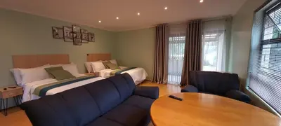 a bedroom with a bed and a couch and a table at Ojong's Self-Catering Ridgeworth - Bellville in Tyger Valley