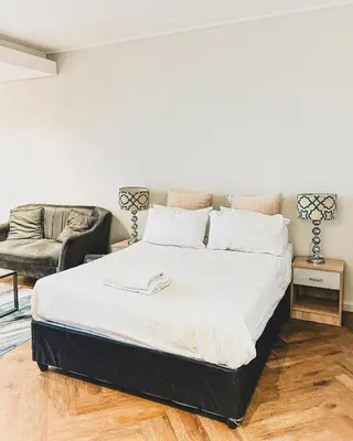 a large bed in a room with a couch at Luxe Studio - On Park near Canal walk Century City in Cape Town
