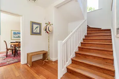 a staircase in a home with white walls and wood floors at Escape to Hermanus Spacious Family Home in Hermanus