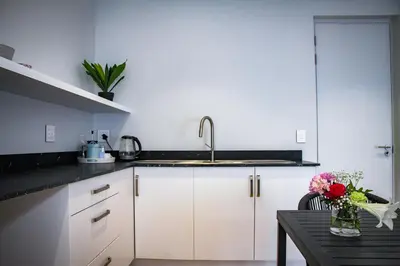 a kitchen with white cabinets and a sink and a table at Upmarket Room in Stellenbosch