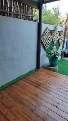 a wooden deck with a potted plant on a patio at Beach Pebble - 200m walk to beach kite surfer paradise, work friendly, pet friendly - must request in Bloubergstrand