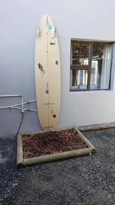 a surfboard leaning against a wall next to a surfboard leaned against a wall at Beach Pebble - 200m walk to beach kite surfer paradise, work friendly, pet friendly - must request in Bloubergstrand