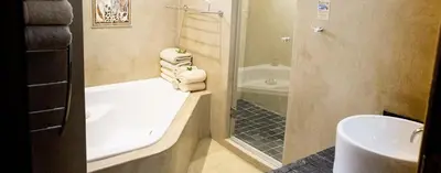 a bathroom with a shower and a tub and a sink at Kapensis Guesthouse II Venue & self-catering in Bettyʼs Bay