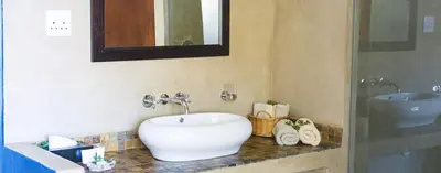 a bathroom with a white sink and a mirror at Kapensis Guesthouse II Venue & self-catering in Bettyʼs Bay