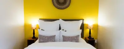 a bedroom with a white bed with two lamps at Kapensis Guesthouse II Venue & self-catering in Bettyʼs Bay