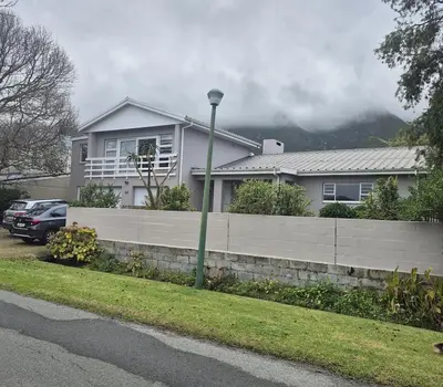 a house with a retaining wall and a fence at Serendipity 2 Bedroom Family Home in Onrus in Hermanus