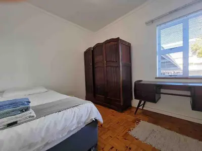a bedroom with a bed and a dresser next to a window at Sunny Spacious Stellenbosch 3 bed garden apartment in Stellenbosch