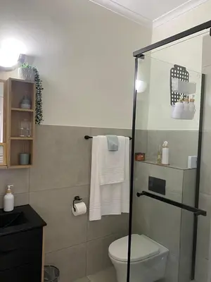 a bathroom with a shower and a toilet and towels at Nunu's Self Catering Apartment in Paarl