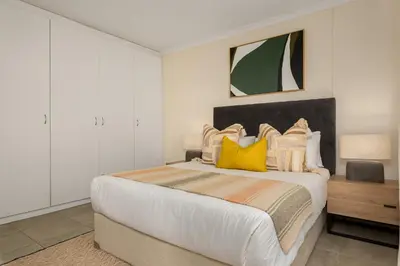 a bedroom with a large bed with yellow pillows at Elegant Apartment with Pool and Balcony Views in Cape Town