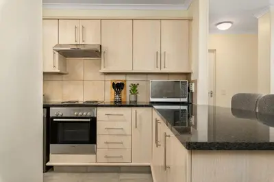a kitchen with white cabinets and black counter tops at Elegant Apartment with Pool and Balcony Views in Cape Town
