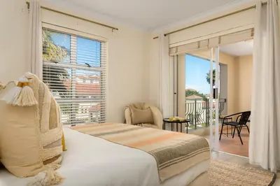 a bedroom with a bed and a large window at Elegant Apartment with Pool and Balcony Views in Cape Town