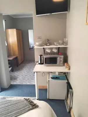 a small kitchen with a microwave on a table at Impletio in Gordonʼs Bay