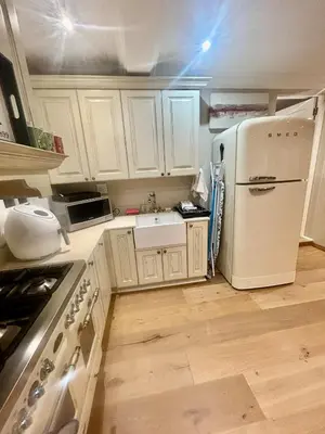 a kitchen with white cabinets and a white refrigerator at French Manor 1 in Stellenbosch