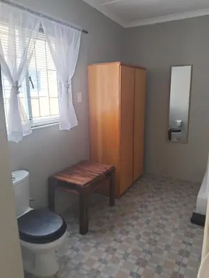 a bathroom with a toilet and a wooden cabinet at Impletio in Gordonʼs Bay