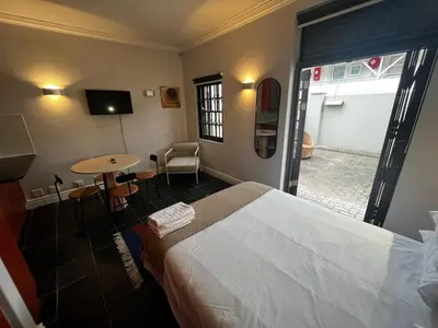 a hotel room with a bed and a table and a desk at Live Like a Local in Stellies - By ARPA Hospitalities in Stellenbosch