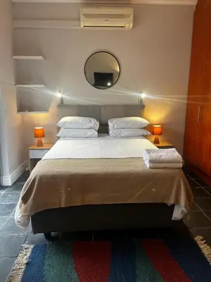a bedroom with a bed with two lamps and a mirror at Live Like a Local in Stellies - By ARPA Hospitalities in Stellenbosch